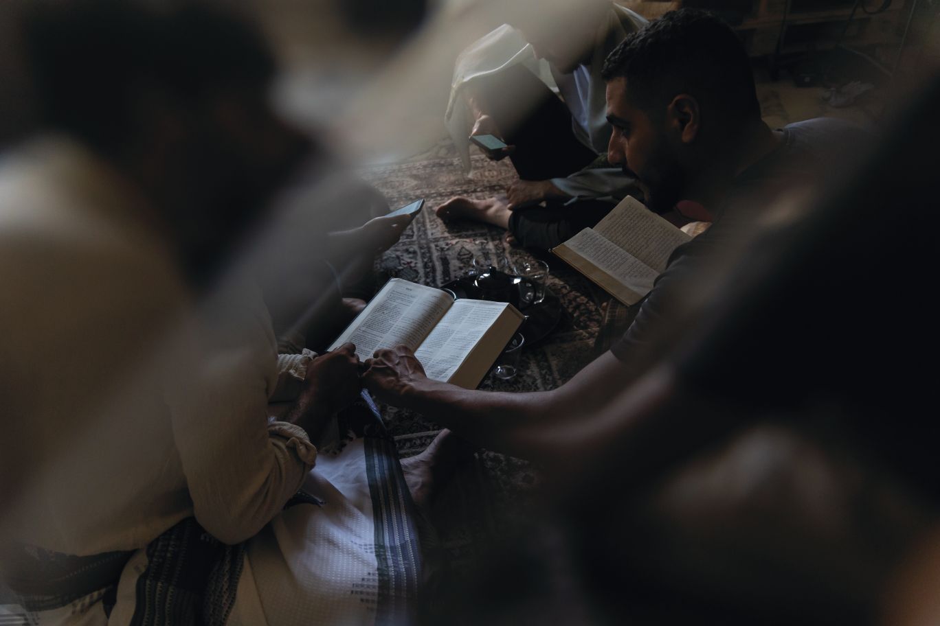 Muži na zemi čítajú Bibliu.